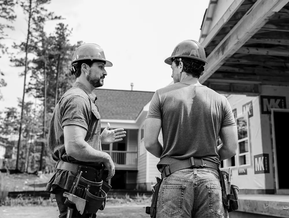 Dos trabajadores de la construcción hablando en la entrada de su casa